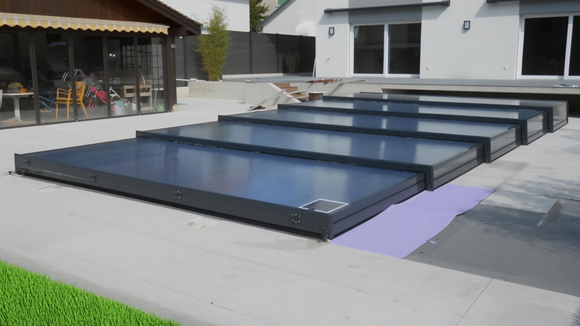 Abri de piscine plat Europa télescopique installé dans un jardin en Suisse romande