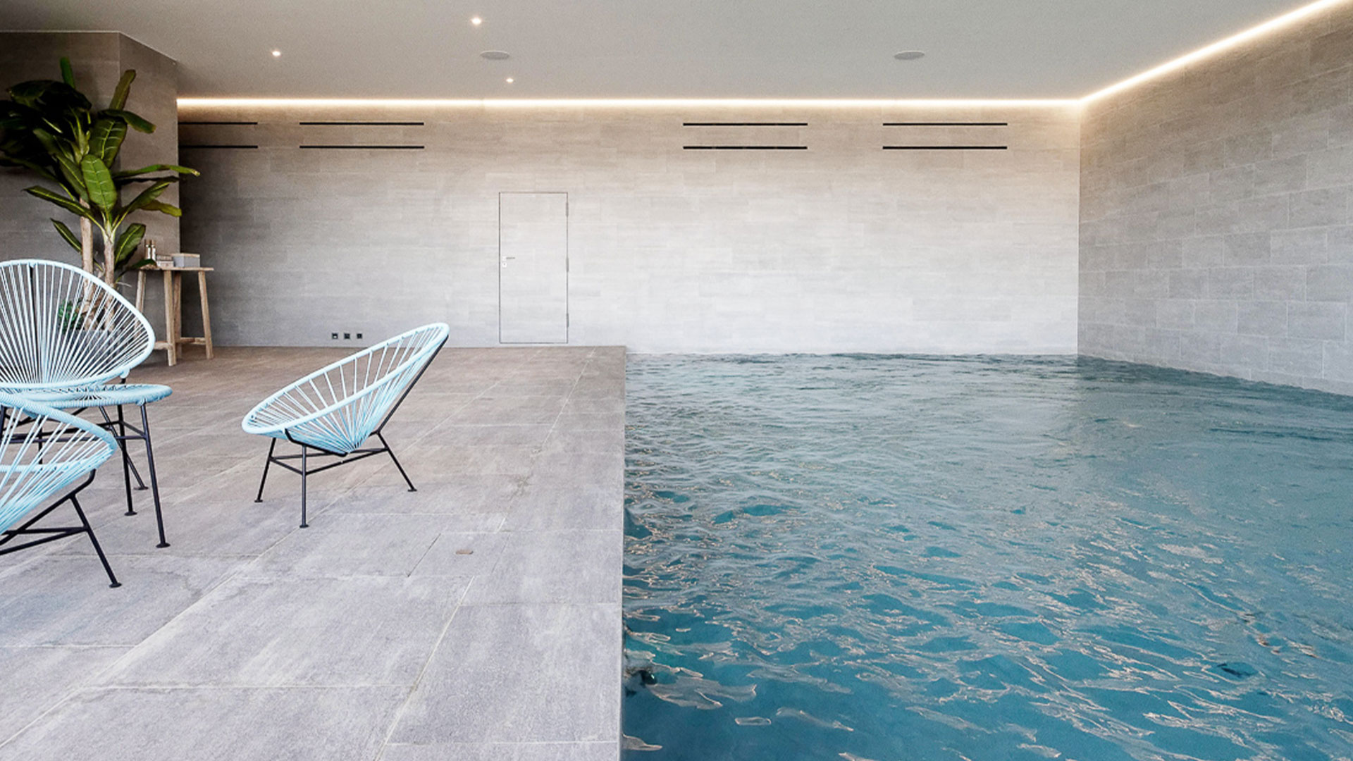 Construction piscine intérieure avec carrelage piscine terrasse et murs gris à Cologny