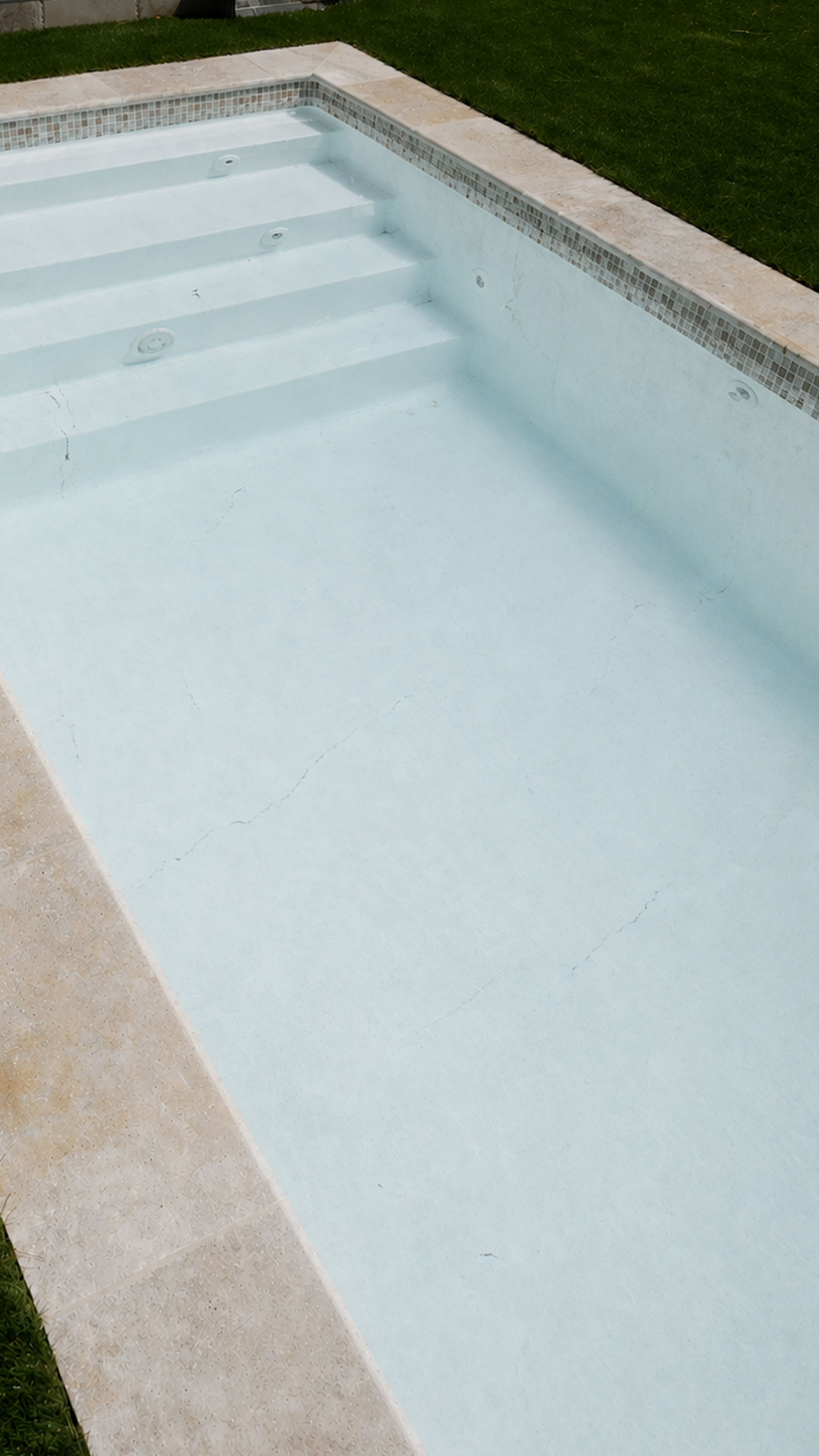 Coque piscine jaunie et gel coat décoloré avec fissures et osmose sur Genève